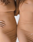 Product shot of NŪD Apparel Tayler Slip Dress, wide strap, fitted style and seamless, made of bamboo fabric produced in California, in Medium Nude  on fair-skinned model, front close-up shot