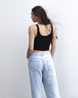 Product shot of NŪD Apparel Devon Double Layered Scoop Crop top, wide strap and seamless, made of bamboo fabric produced in California, in Black on fair-skinned model paired with light-wash jeans, back shot