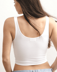 Product shot of NŪD Apparel Devon Double Layered Scoop Crop top, wide strap and seamless, made of bamboo fabric produced in California, in White on fair-skinned model paired with light-wash jeans, close-up back shot