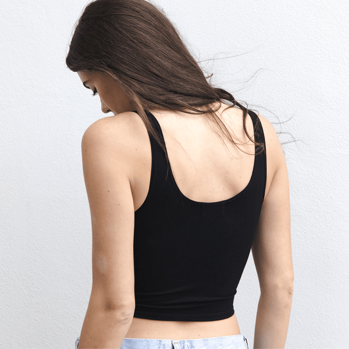 Product shot of NŪD Apparel Devon Double Layered Scoop Crop top, wide strap and seamless, made of bamboo fabric produced in California, in Black on fair-skinned model paired with light-wash jeans, back shot
