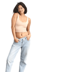 Product shot of NŪD Apparel Devon Double Layered Scoop Crop top, wide strap and seamless, made of bamboo fabric produced in California, in Light Nude on fair-skinned model paired with light-wash jeans, front wide shot