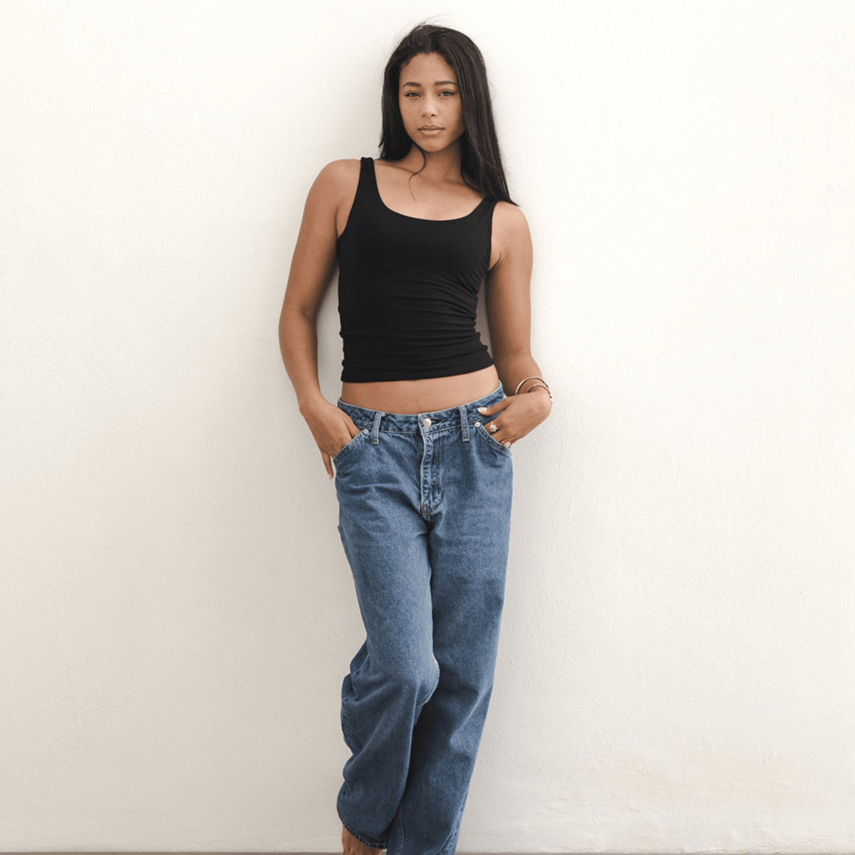 Product shot NŪD Apparel Devon Long Double Layer Scoop, wide strap, perfect length and seamless, made of bamboo fabric produced in California, in Black on medium-skinned model paired with dark-wash jeans, front wide shot