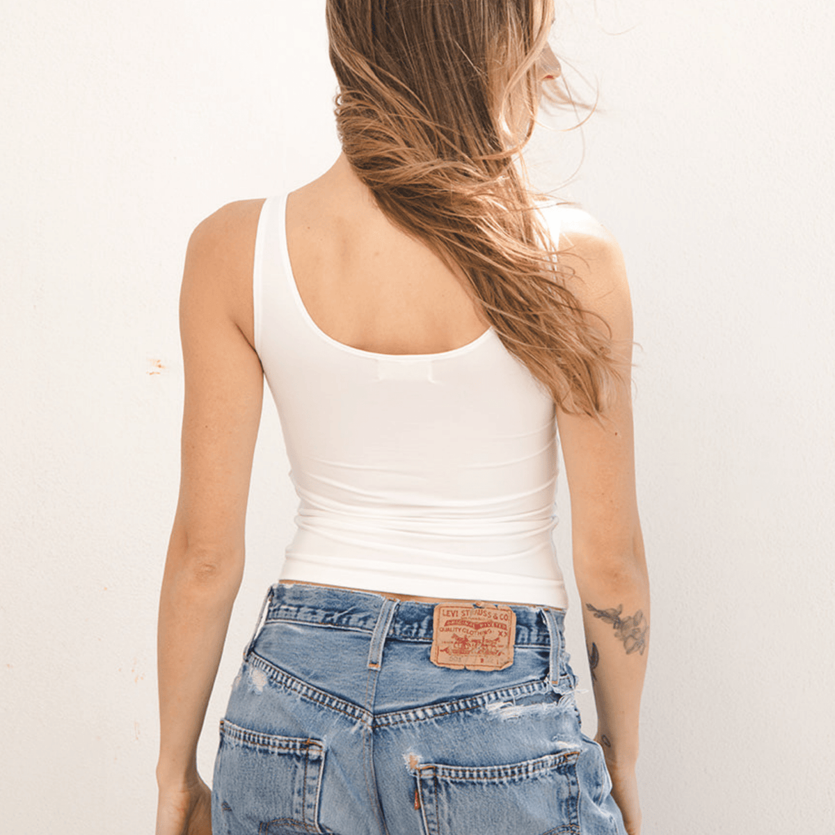 Product shot NŪD Apparel Devon Long Double Layer Scoop, wide strap, perfect length and seamless, made of bamboo fabric produced in California, in White on fair-skinned model paired with light-wash jeans, back shot