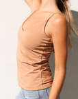 Product shot of NŪD Apparel Nesha Double Layered Tank, thin strap, long style and seamless, made of bamboo fabric produced in California, in Medium Nude on fair-skinned model paired with light-wash jeans, side shot