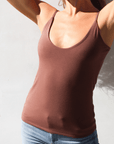 Product shot of NŪD Apparel Nesha Double Layered Tank, thin strap, long style and seamless, made of bamboo fabric produced in California, in Dark Nude on fair-skinned model paired with light-wash jeans, front shot