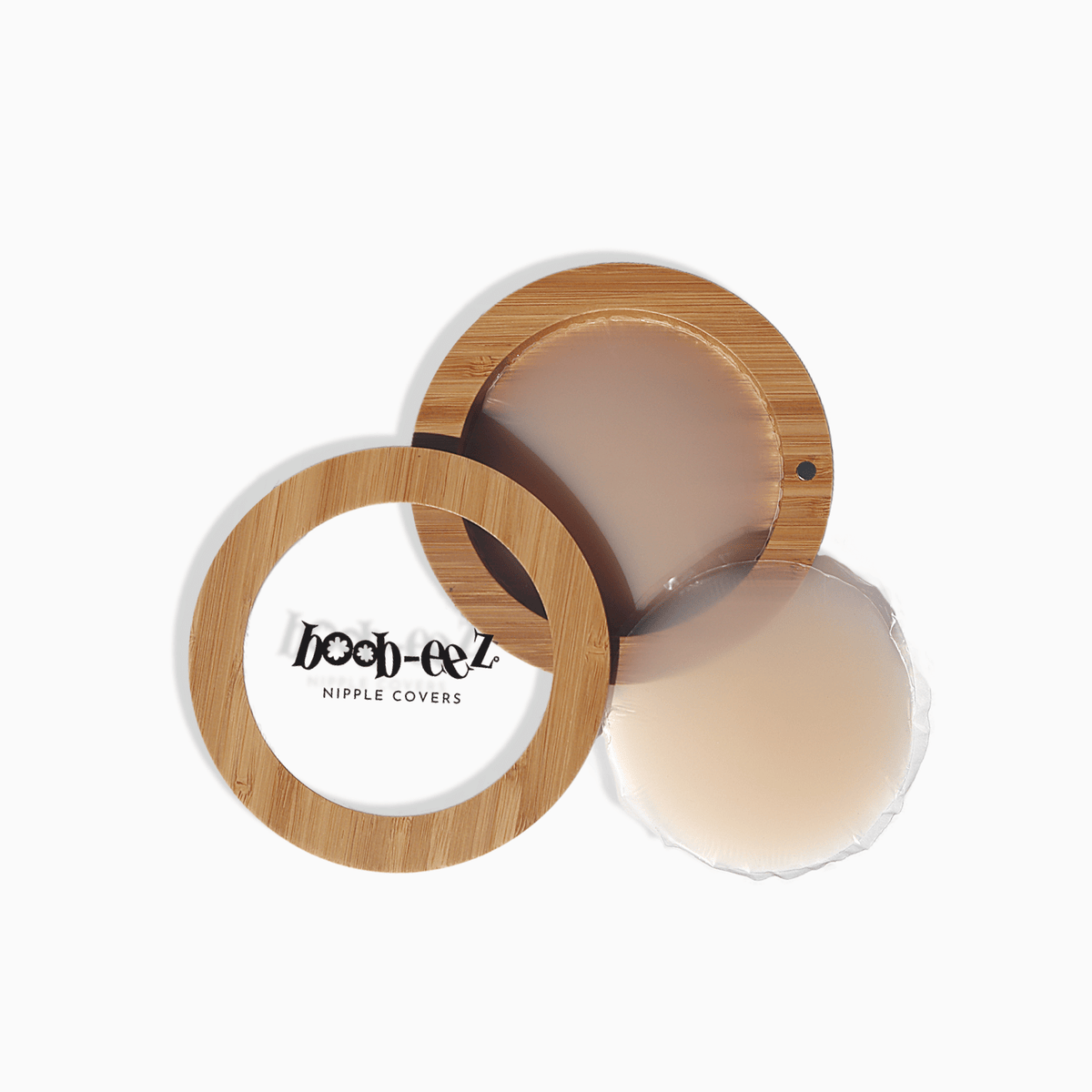 Product shot of Boob-eez Bamboo Compact with 6cm Light tint Headlight Hiders inside and informative insert cards with wear and care instructions, close-up shot showing how to open and close the Bamboo Compact